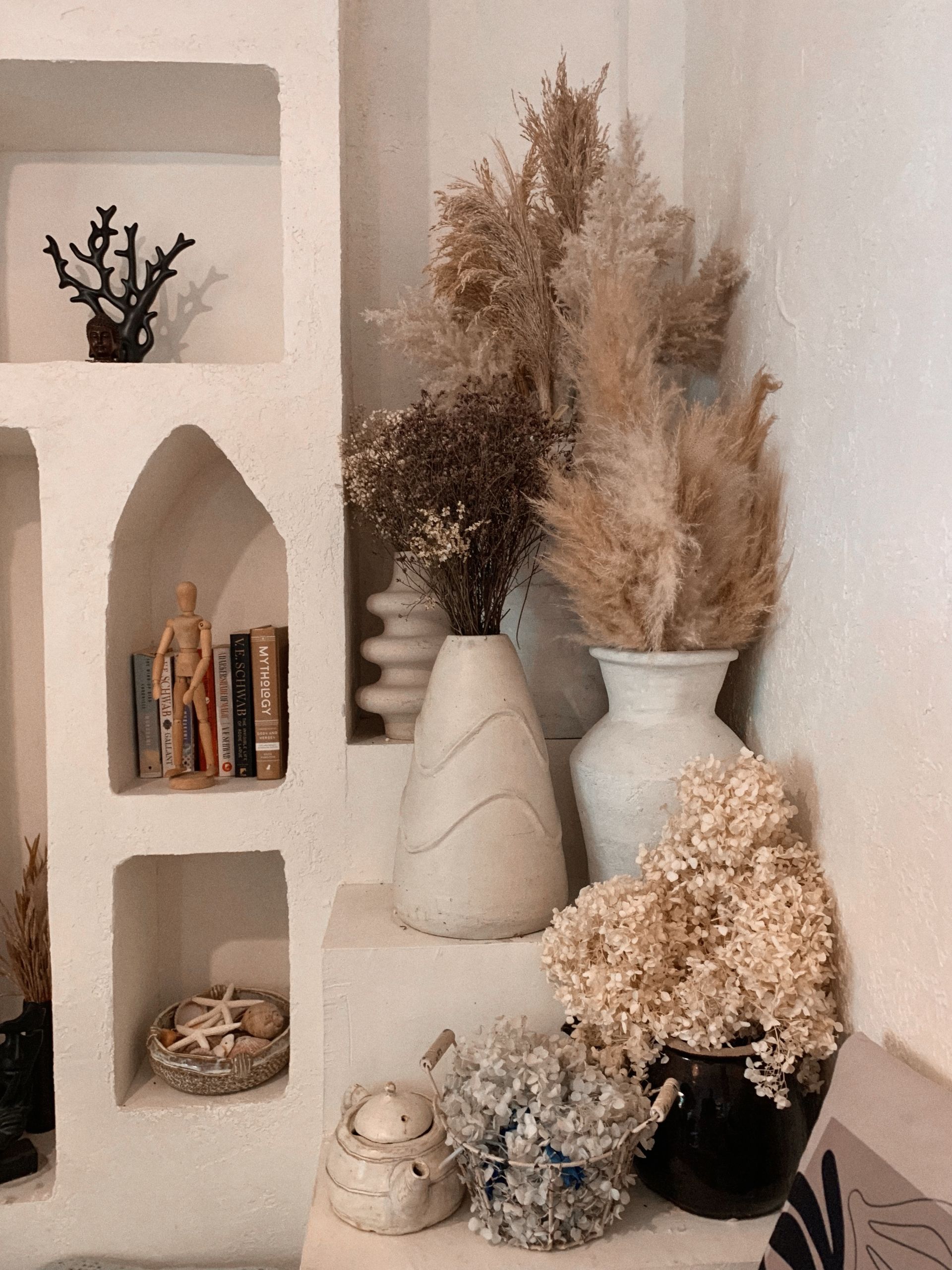 Boho chic room decor featuring dried flowers, vases, and shelves. Cozy and rustic.