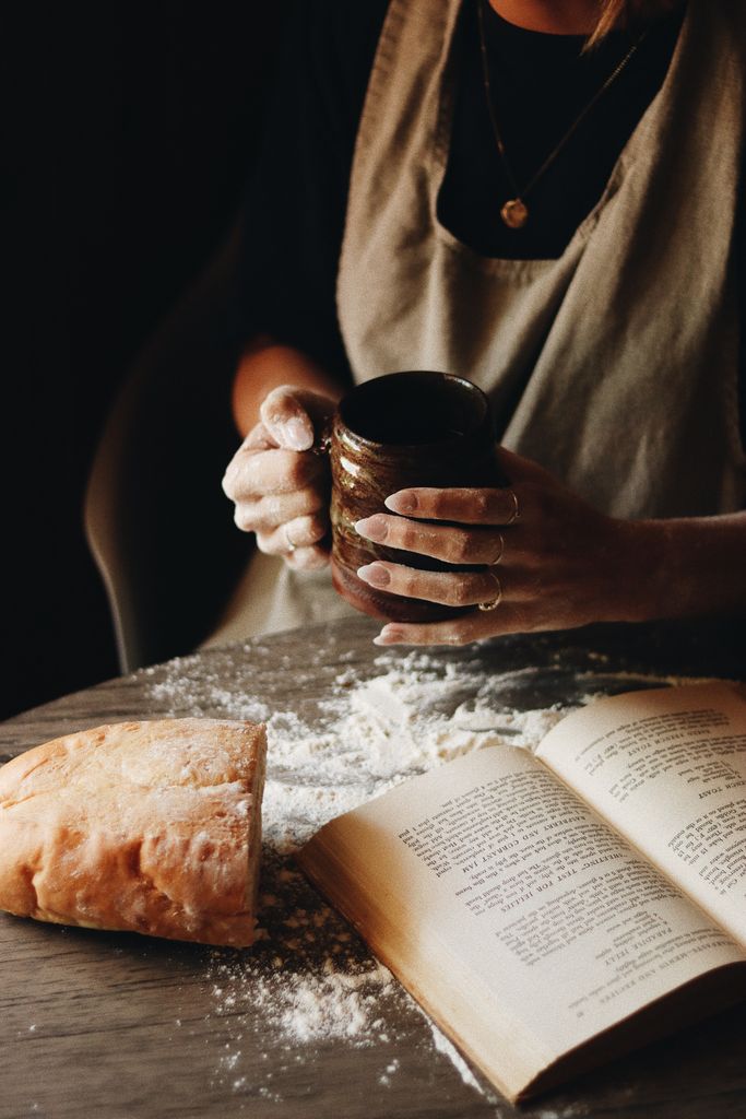 Warm and inviting scene of a woman baking bread with coffee and a recipe book.